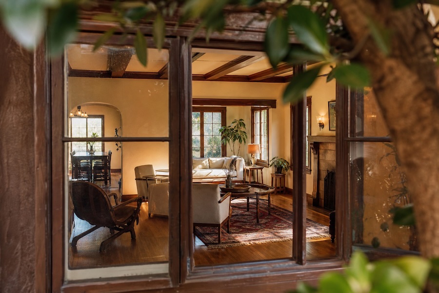 Spanish-style living room with exposed wood beams, hardwood floors, a fireplace, and an adjoining dining area.